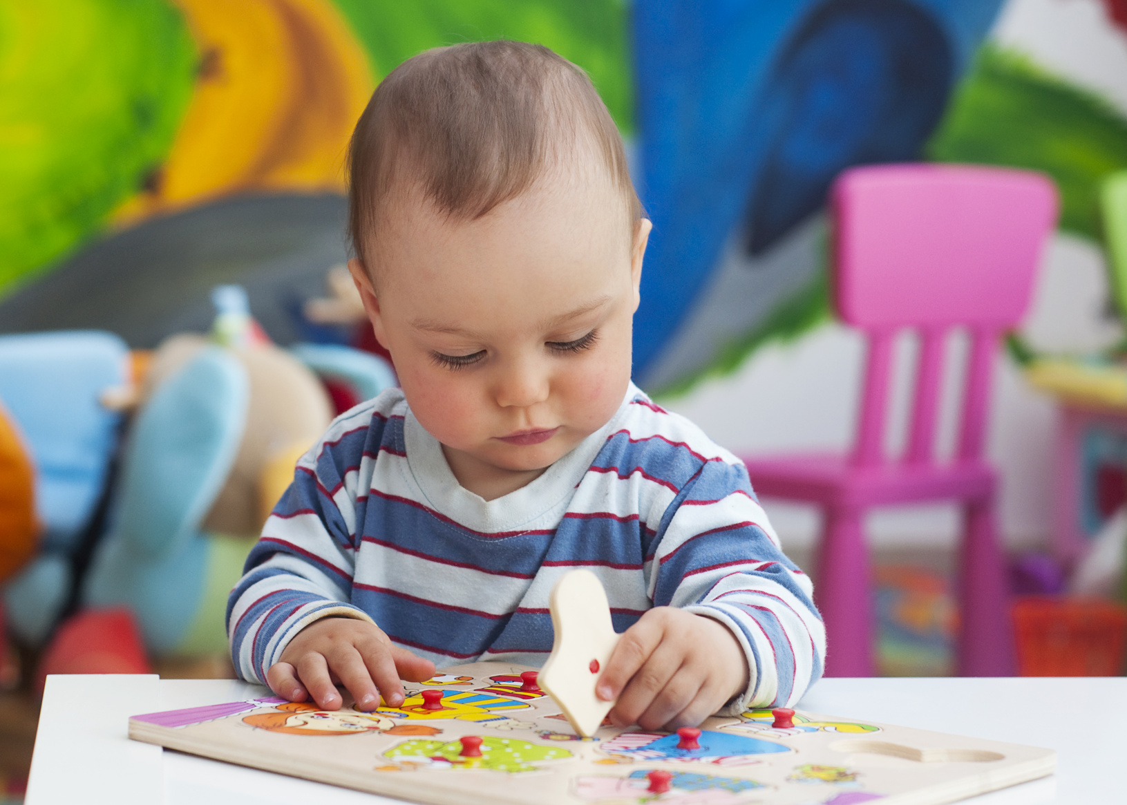 Toddler or a baby child playing with puzzle in a nursery.