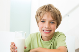 Portrait of happy boy with glass of milk at home